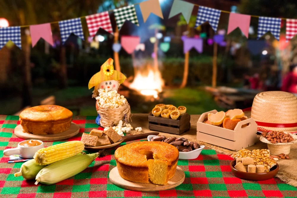 Bolos e comidas a base de milho e mandioca em uma mesa típica de festa junina.